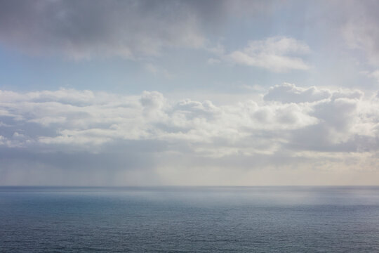 White clouds in a blue sky over the Pacific ocean at dusk