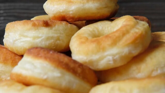 Delicious donuts spinning against wood rustic wall. Donut stack is turning in a candy shop showcase. Rotating close-up shot. Pastry, sweet rotation. Homemade deep fried dessert. Bakery, confectionery.