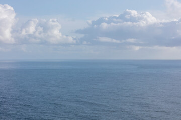 White clouds in a blue sky over the Pacific ocean at dusk
