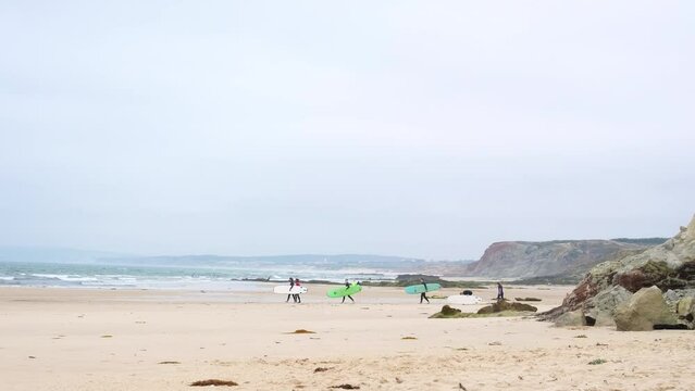 Surfers walking on the beach by the ocean with their surfboards plan to go surfing