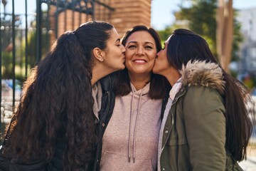 Three woman mother and daughters standing together and kissing at street