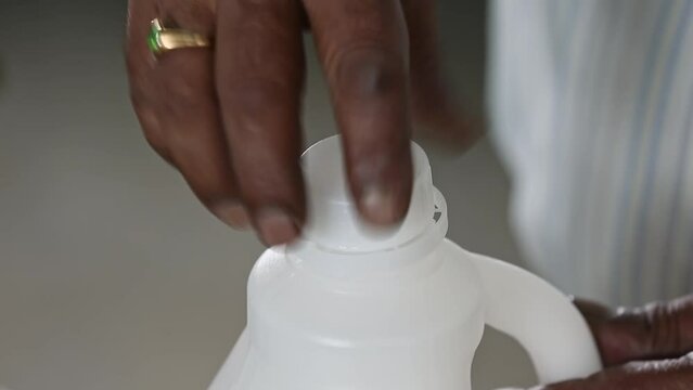 The manual placement of caps on filled plastic bottles of detergent at the factory