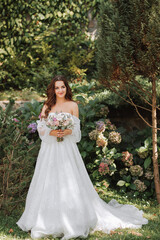Obraz na płótnie Canvas young and beautiful bride with long brown hair in a wedding dress outdoors with a wedding bouquet of flowers. Full-length portrait