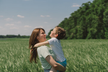 Happy Mother's Day. Little boy and mother is playing in a green barley field. People and nature. Rural scene