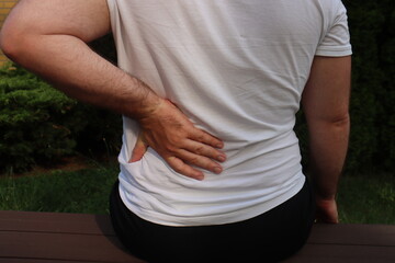 A man holds his back with his left hand because she has an injury or hurts