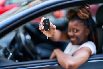 Fototapeta na wymiar African american woman smiling confident holding key of new car at street