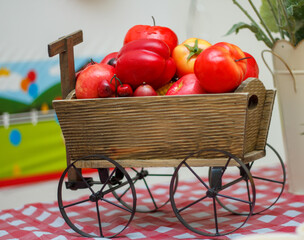 A wooden decorative cart with fruits and vegetables. The cart is on table