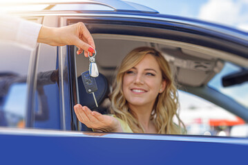 A woman's hand passes the key to the car. Buying a car or renting.