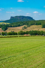 Fototapeta na wymiar Königstein, Saxony, Germany. View Lilienstein mount in the national park Saxon Switzerland by Elbe river and green countryside fields and forests
