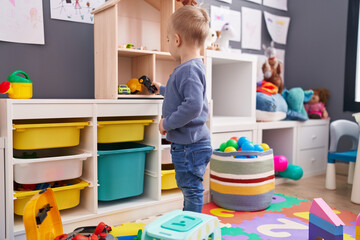 Adorable caucasian boy playing on back view at kindergarten