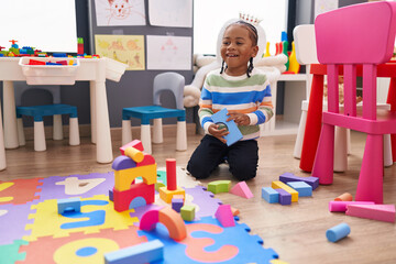 African american boy playing with construction blocks sitting on floor at kindergarten