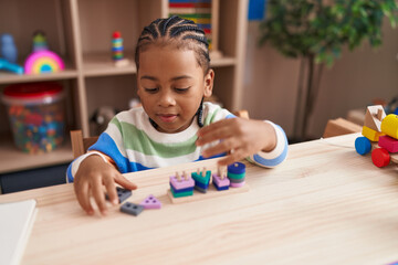 African american boy playing with blocks game sitting on table at kindergarten