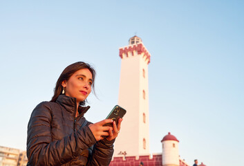 portrait young adult latin american woman with cell phone in hand looking at the horizon