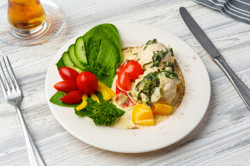 Chicken breast cooked in sauce and fresh vegetables served on plate in cafe