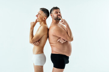 Fototapeta na wymiar multiethnic men posing for a male edition body positive beauty set showing messages on banners. Shirtless guys with different age, and body wearing boxers underwear