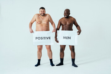 multiethnic men posing for a male edition body positive beauty set showing messages on banners....