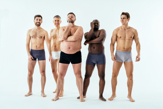 multiethnic men posing for a male edition body positive beauty set showing messages on banners. Shirtless guys with different age, and body wearing boxers underwear