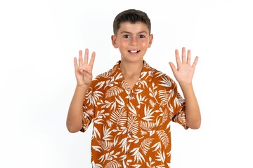 Little hispanic boy wearing  hawaiian shirt  showing and pointing up with fingers number nine while...