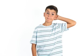Little hispanic boy wearing  striped T-shirt  being confused and wonders about something. Holding hand on head, uncertain with doubt. Pensive concept.