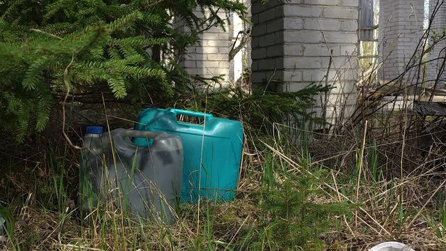 Two big gasoline container on the grassy lawn on the forest near the abandoned house in Estonia