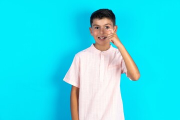 Little hispanic boy wearing white shirt  pointing up with fingers number nine in Chinese sign...