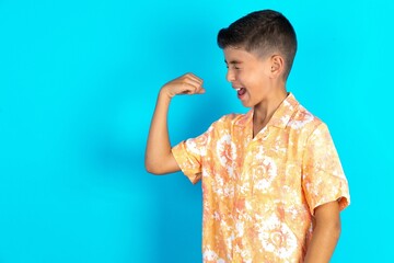 Portrait of funny Little hispanic boy wearing hawaiian shirt  shout yeah raise fists hands...