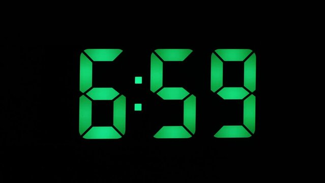 Green seven-segment numbers LED clock close-up, shows 7-00 am, the concept of the beginning of the working day