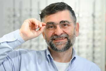 male customer choosing glasses in optics store