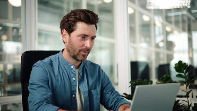 Serious handsome businessman sitting at remote workplace with laptop computer. Pensive professional thinking at table in office. Focused business man face looking around. Working man portrait.
