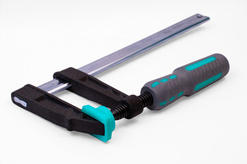 metal adjustable clamp on a white background. industrial powerful clamp on the table. wood gluing concept. fixing device on a work texture