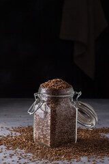 Flax seeds in a glass jar on a gray textured background. Healthy food, superfood