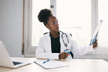 African American physician examining x ray image at table
