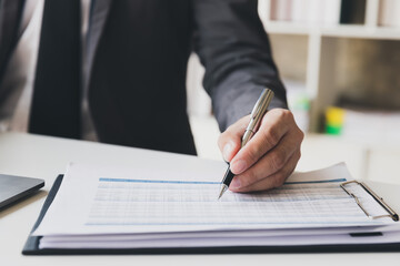 Businessman pointing monthly graph chart. Data analyzing to find out the result. Businessman writing or pointing on report paper. Business strategy concept.