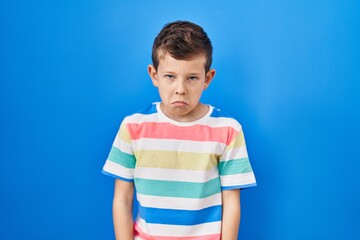 Young caucasian kid standing over blue background depressed and worry for distress, crying angry and afraid. sad expression.