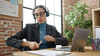 Fototapeta premium Young beautiful hispanic woman business worker dancing using laptop at office