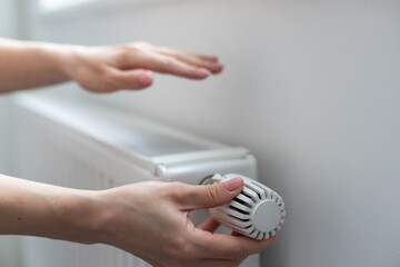 Woman's hand adjusting radiator temperature