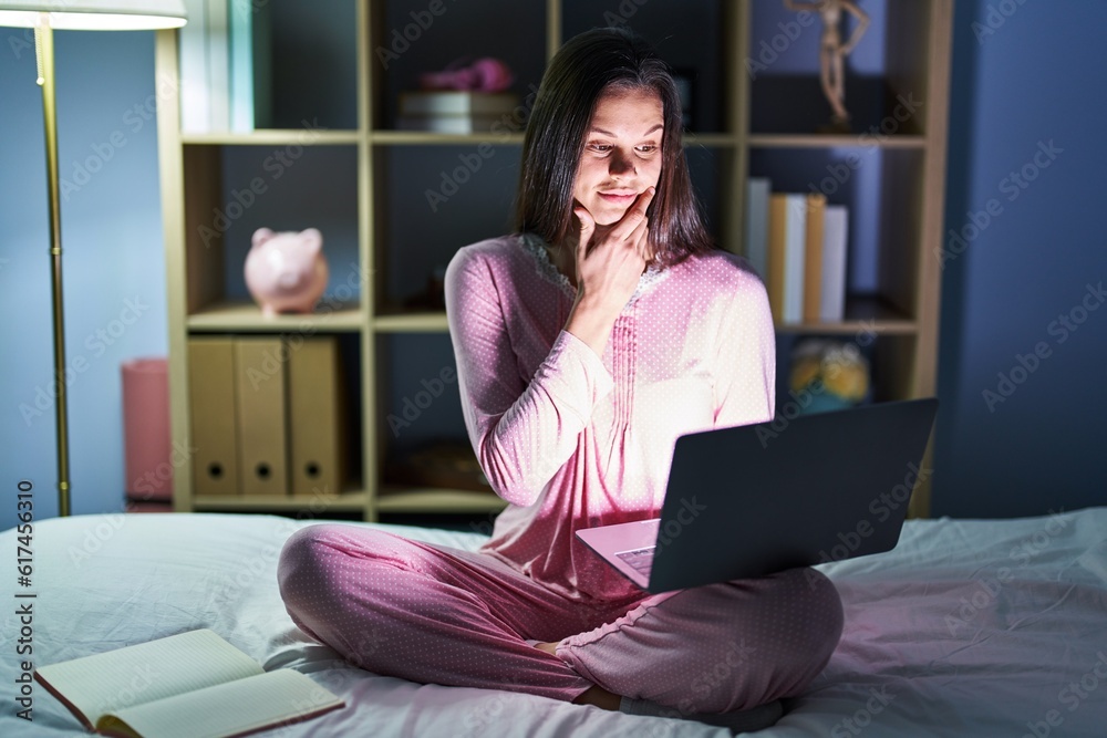 Wall mural young hispanic woman using computer laptop on the bed looking confident at the camera smiling with c