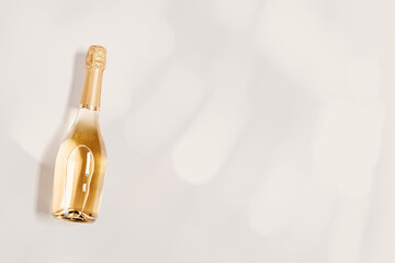 Top view sparkling white wine, bottle of champagne wine with sunlight flare on beige background,...