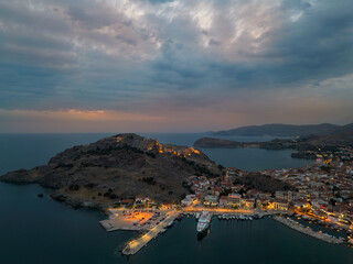 Aerial view of the port of Myrina in Lemnos with ships and the illuminated castle in the background