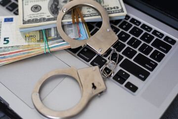 Police handcuffs lie on a lot of dollar bills. The concept of illegal possession of money, illegal...
