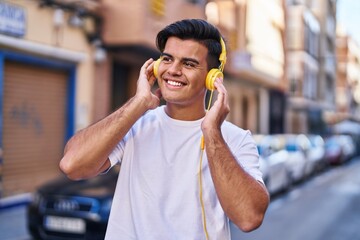 Young hispanic man listening to music at street
