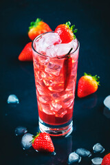 Red alcoholic cocktail drink with vodka, grapefruit juice, strawberries, sugar and hot chili pepper. Highball glass on dark blue background