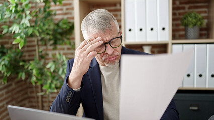 Fototapeta premium Middle age grey-haired man business worker stressed reading document at office