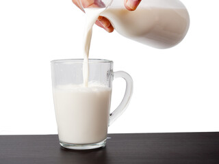 Milk is poured from a bottle into a glass. Milk on a light background.