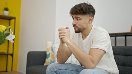 Young arab man sitting on sofa with relaxed expression at home