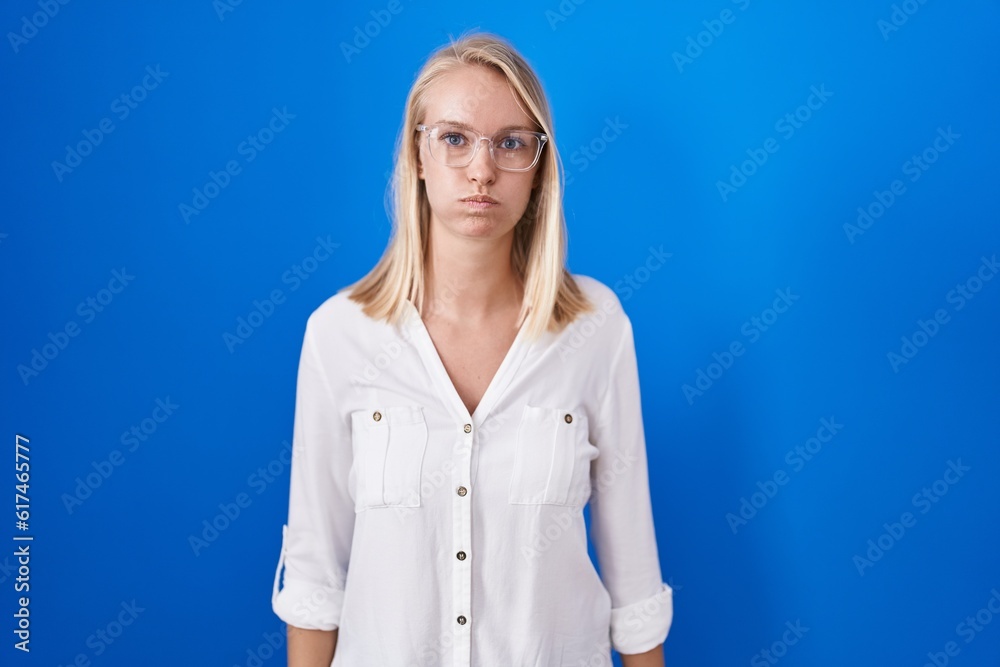 Canvas Prints young caucasian woman standing over blue background puffing cheeks with funny face. mouth inflated w