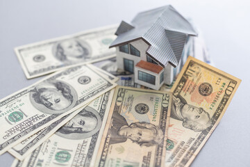 Wooden house model on background of US dollars banknotes. Housing market, purchase or rental of real estate. The concept of buying and selling real estate