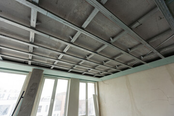 Workers are installing plasterboard (drywall) for gypsum walls in apartment is under construction,...