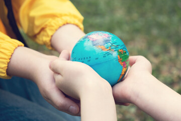 Children kid girl in a yellow raincoat and boy holding globe in a hands outdoor in park or forest....