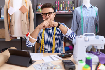 Hispanic man with beard dressmaker designer working at atelier rejection expression crossing fingers doing negative sign